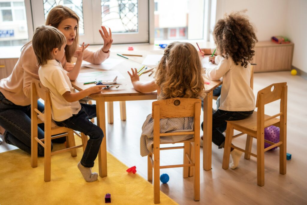 educator teaching multicultural kids counting and showing number with fingers in kindergarten